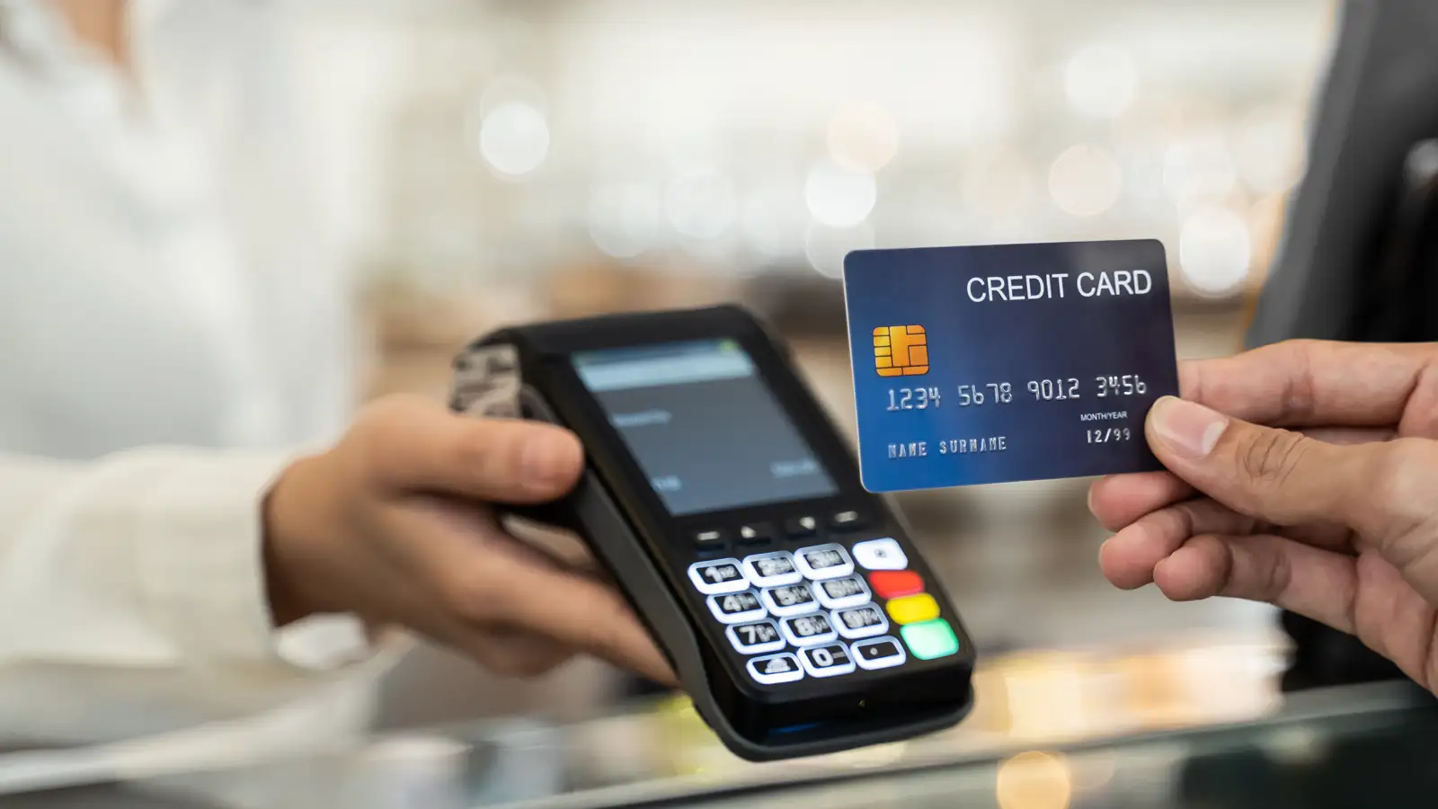 Customer holding a credit card beside an EFTPOS payment terminal